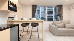 A compact living space with a kitchenette, a sofa, and a window with curtains.