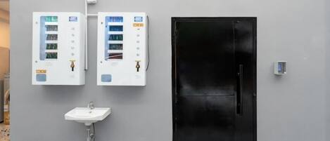 A bathroom with a sink, two electrical panels, and a black door.