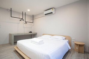 Una camera d'albergo moderna con un letto, un comodino e una panca integrata.