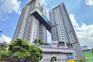 Un edificio alto con varios pisos, un llamativo letrero que dice 'VERVE Suites', y un cielo despejado con nubes.