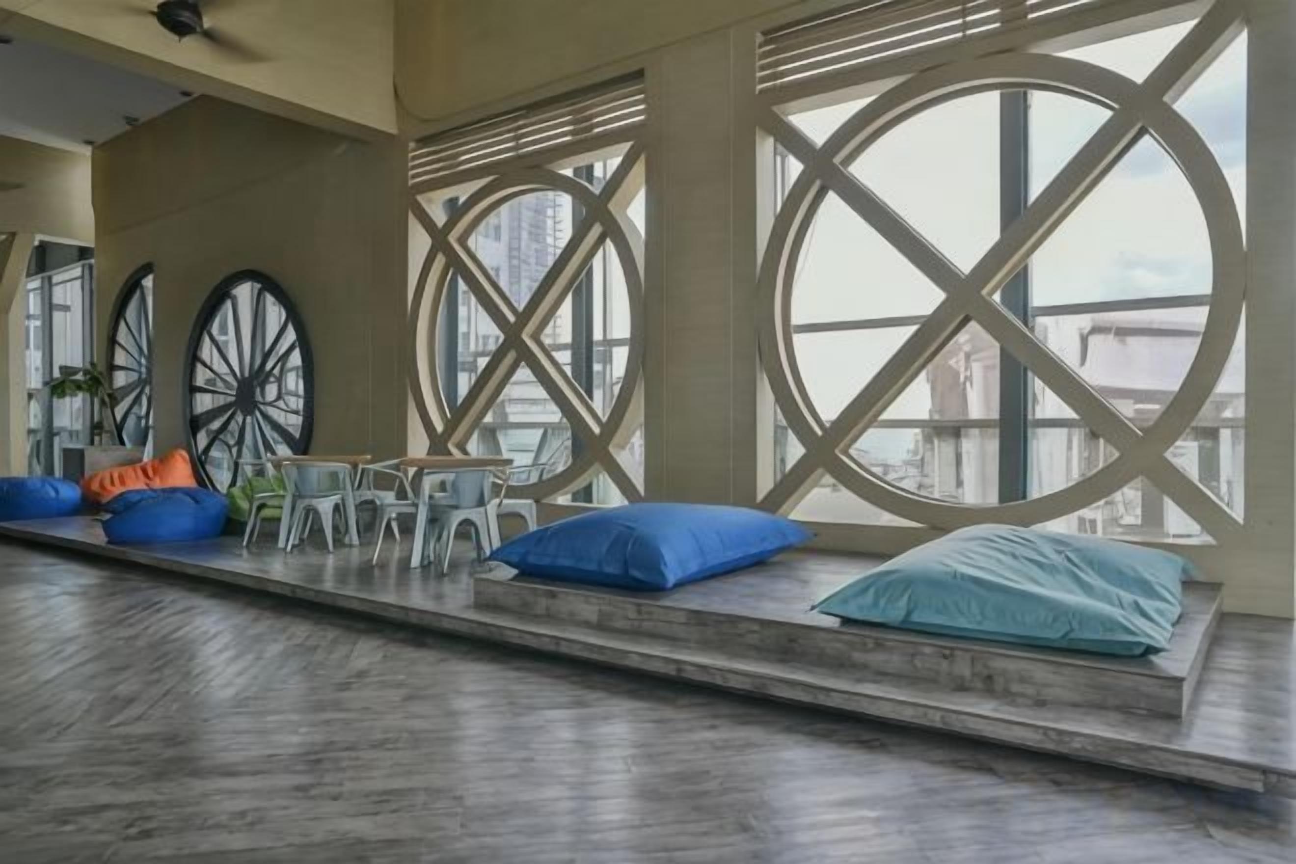 Un espacio de descanso con vista a la ciudad, que incluye un banco con cojines y una mesa con sillas.