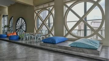 Un espacio de descanso con vista a la ciudad, que incluye un banco con cojines y una mesa con sillas.