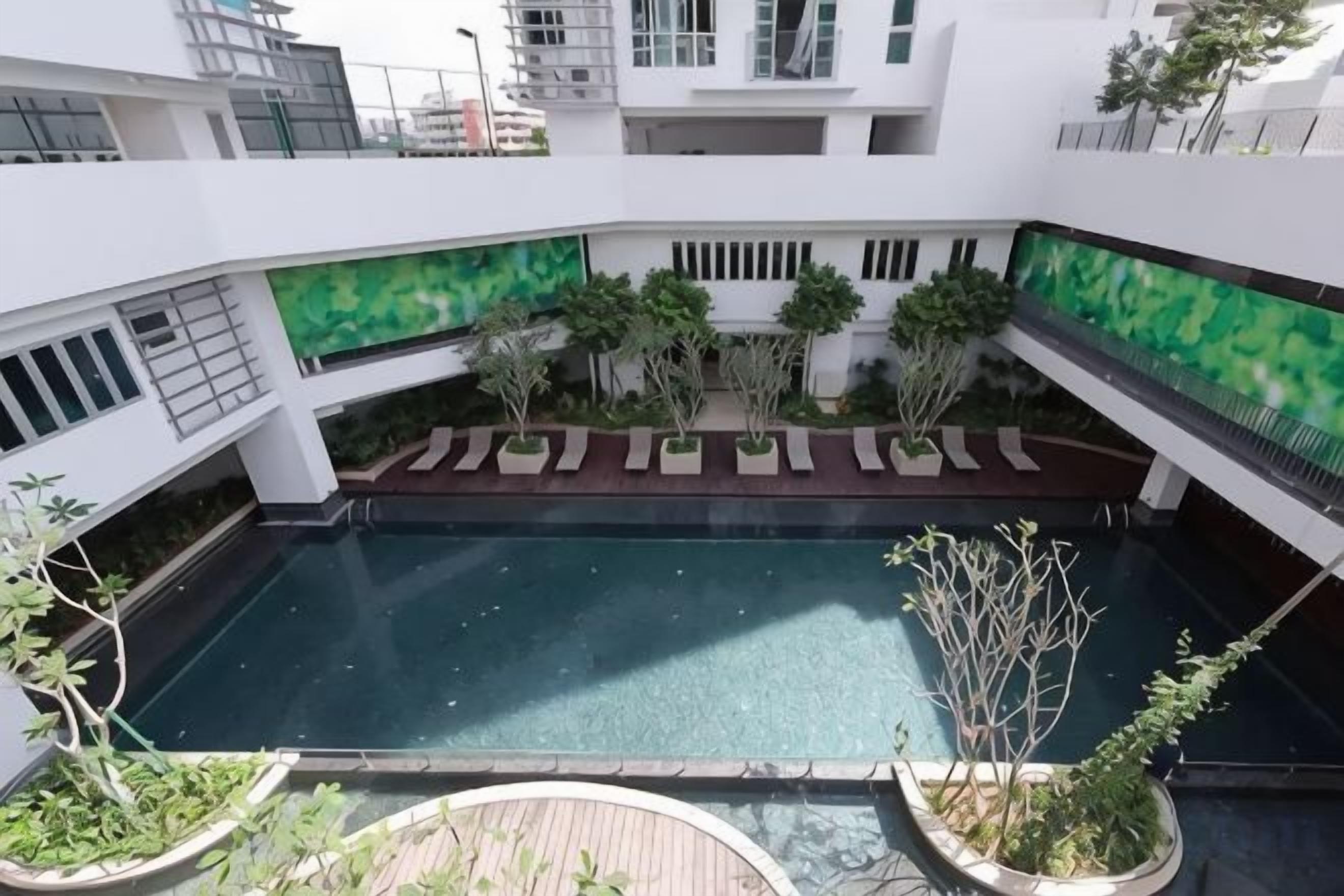 Una piscina en la azotea rodeada de vegetación y un edificio de estructura moderna.
