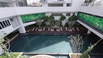 Una piscina en la azotea rodeada de vegetación y un edificio de estructura moderna.
