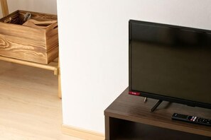A television on a wooden stand with a remote control beside it. - Vacation Stay Fushimiinari (Kyoto)