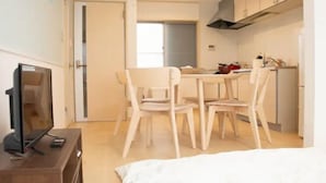 A compact room with a bed, a TV, a dining table with chairs, and a kitchenette. - Vacation Stay Fushimiinari (Kyoto)