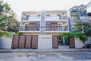 A two-story building with a gated entrance, balconies, and a visible sign indicating the name.