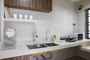 A kitchen with a double sink, white countertop, wooden cabinets, and a microwave. - IpohComfortHomestay, 4-10pax 10mins to attraction (Ipoh)