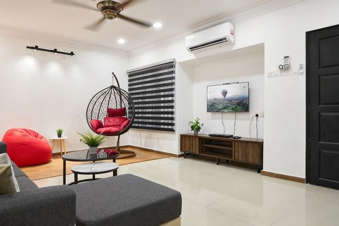 A modern living room with a sofa, red bean bag, hanging chair, TV, and wooden cabinet.