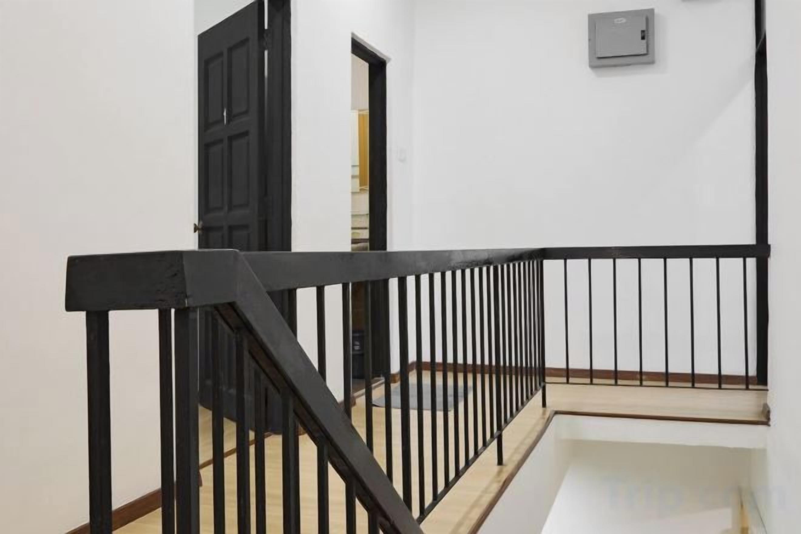 A staircase with a black metal railing, a white wall, and a door leading to another room.