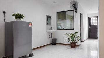 A clean, modern kitchen with a refrigerator, sink, and potted plants.