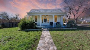 A single-story house with a porch, a stone pathway leading to the entrance, and a small garden area. - Moment in Time - Hot Tub & Fire Pit (Fredericksburg)