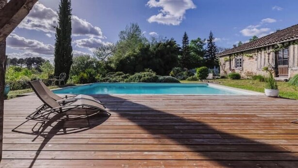 A wooden deck with a pool, surrounded by greenery and a clear sky. - Domaine de la Grotte (Wine Estate) (Sore)