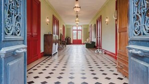 A hallway with a checkered floor, red doors, and decorative metalwork. - Domaine de la Grotte (Wine Estate) (Sore)