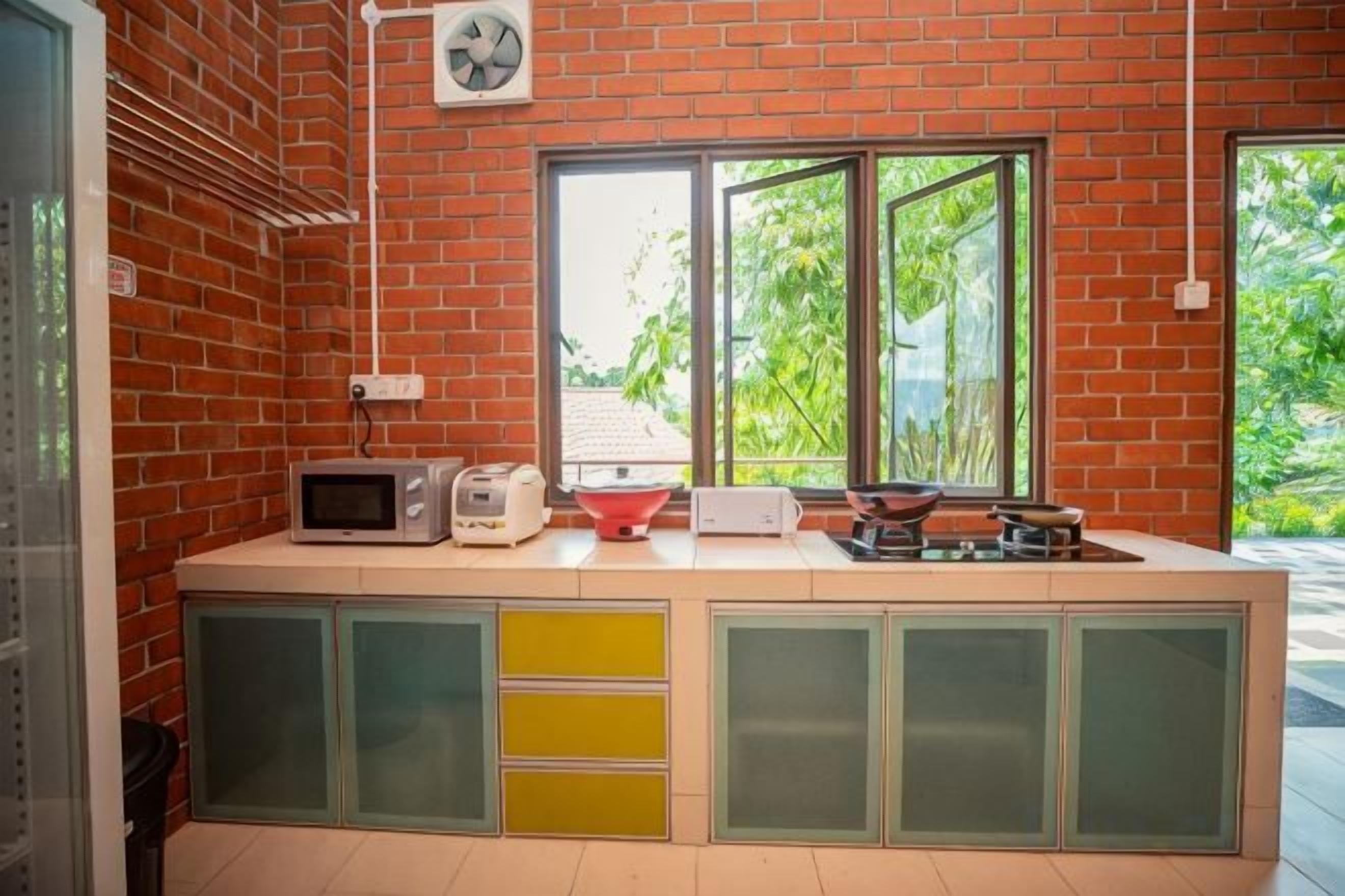 A kitchen with a brick wall, a window, and a microwave on the counter.