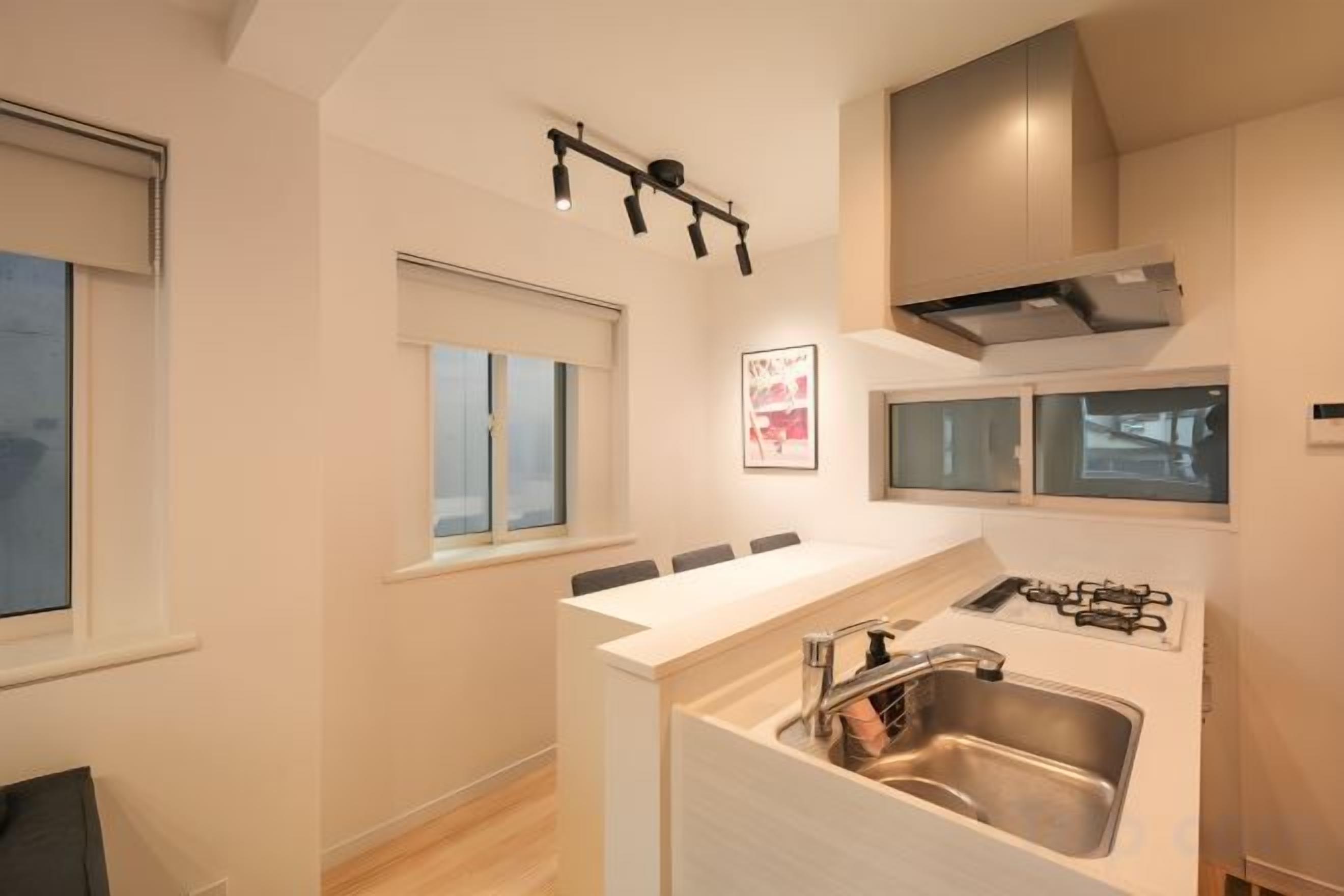 A modern kitchen with a built-in island, stainless steel sink, and overhead lighting.