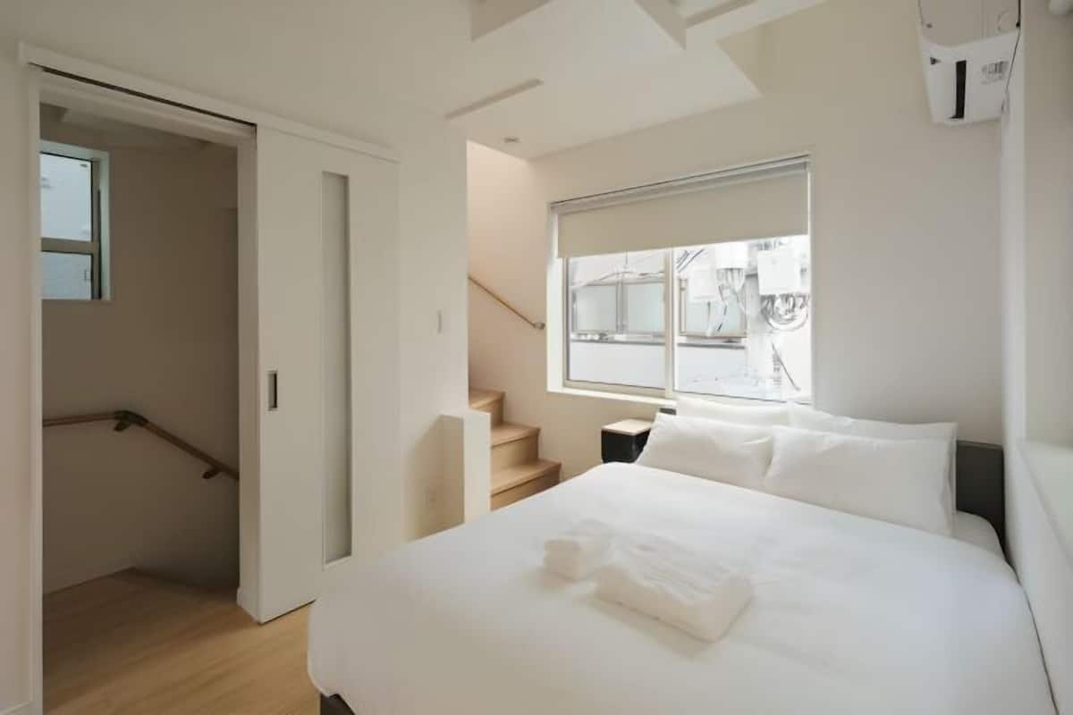 A modern hotel room with a large bed, a window with a view, and a staircase.