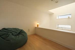 A room with a bean bag chair, a wall-mounted light, and a window. - URBAN HOUSE HATAGAYA (Tokyo)