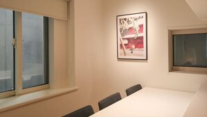 A conference room with a large table, four chairs, a framed picture on the wall, and a window with blinds. - URBAN HOUSE HATAGAYA (Tokyo)
