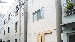 A row of residential buildings with a light-colored exterior, a central door, and small windows. - URBAN HOUSE HATAGAYA (Tokyo)