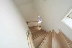 A staircase with wooden steps and a handrail, leading to a landing with a small window. - URBAN HOUSE HATAGAYA (Tokyo)