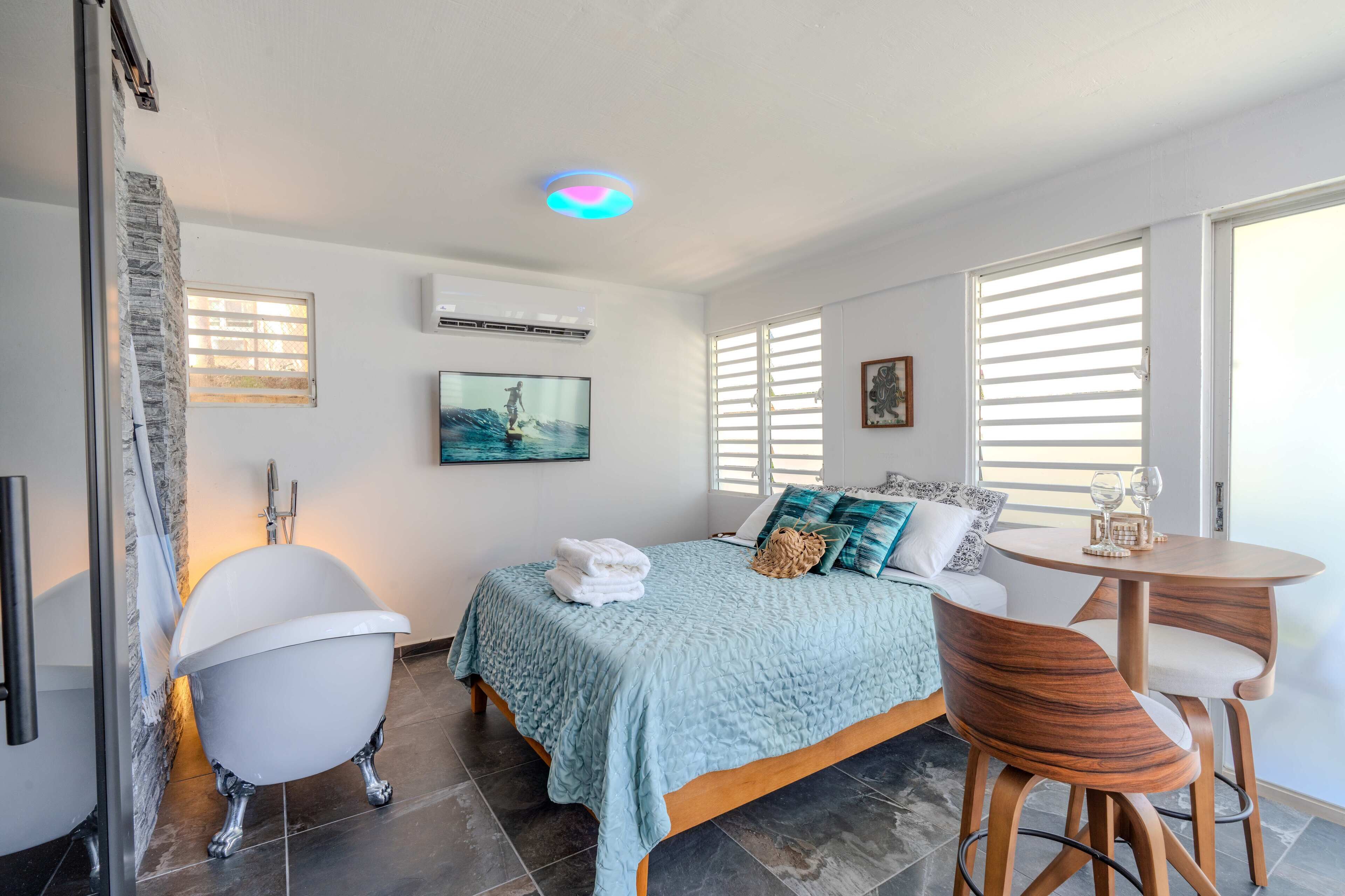 A modern, sunlit space featuring a comfy bed and an elegant tub.