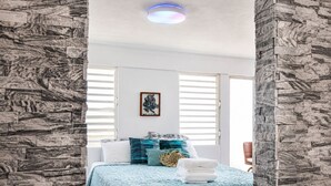 A bedroom with a bed, a wall-mounted picture, and a window with blinds.