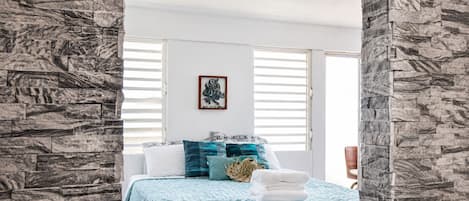 Une chambre à coucher avec un lit, un tableau accroché au mur et une fenêtre avec des stores.