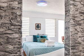 Ein Schlafzimmer mit einem Bett, einem Wandbild und einem Fenster mit Jalousien.