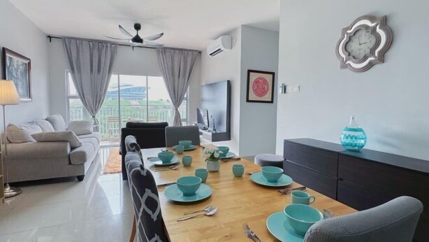 A modern living room with a sofa, dining table set with teal dinnerware, and a view of the city through large windows. - PPAM Seruling Presint 5, Putrajaya 4BR+ PICC View (Putrajaya)