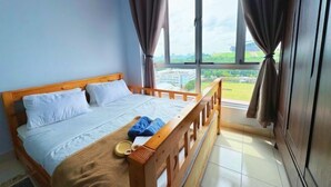 A bedroom with a wooden bed, a window with curtains, and a view of greenery and buildings outside. - PPAM Seruling Presint 5, Putrajaya 4BR+ PICC View (Putrajaya)