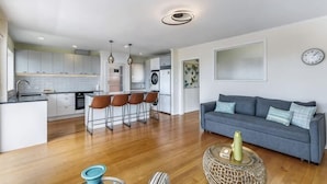 Een moderne keuken met barstoelen, een eetgedeelte met een bank en een woonkamer met een salontafel.