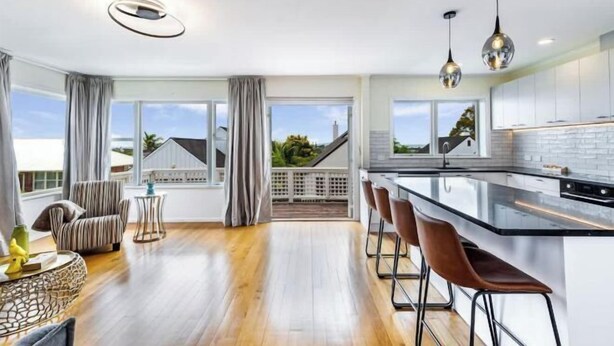 A modern kitchen with a large island, bar stools, and pendant lighting.