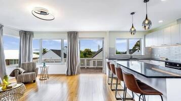 A modern kitchen with a large island, bar stools, and pendant lighting.