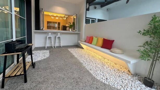Ein modernes Interieur mit einer Sitzecke, einer weißen Bank mit bunten Kissen, einem kleinen Tisch und einer Topfpflanze.