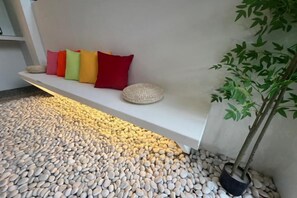 A white bench with colorful cushions and a potted plant beside it. - JIA Residence 21 pax (Karaoke + Snooker) (Ipoh)