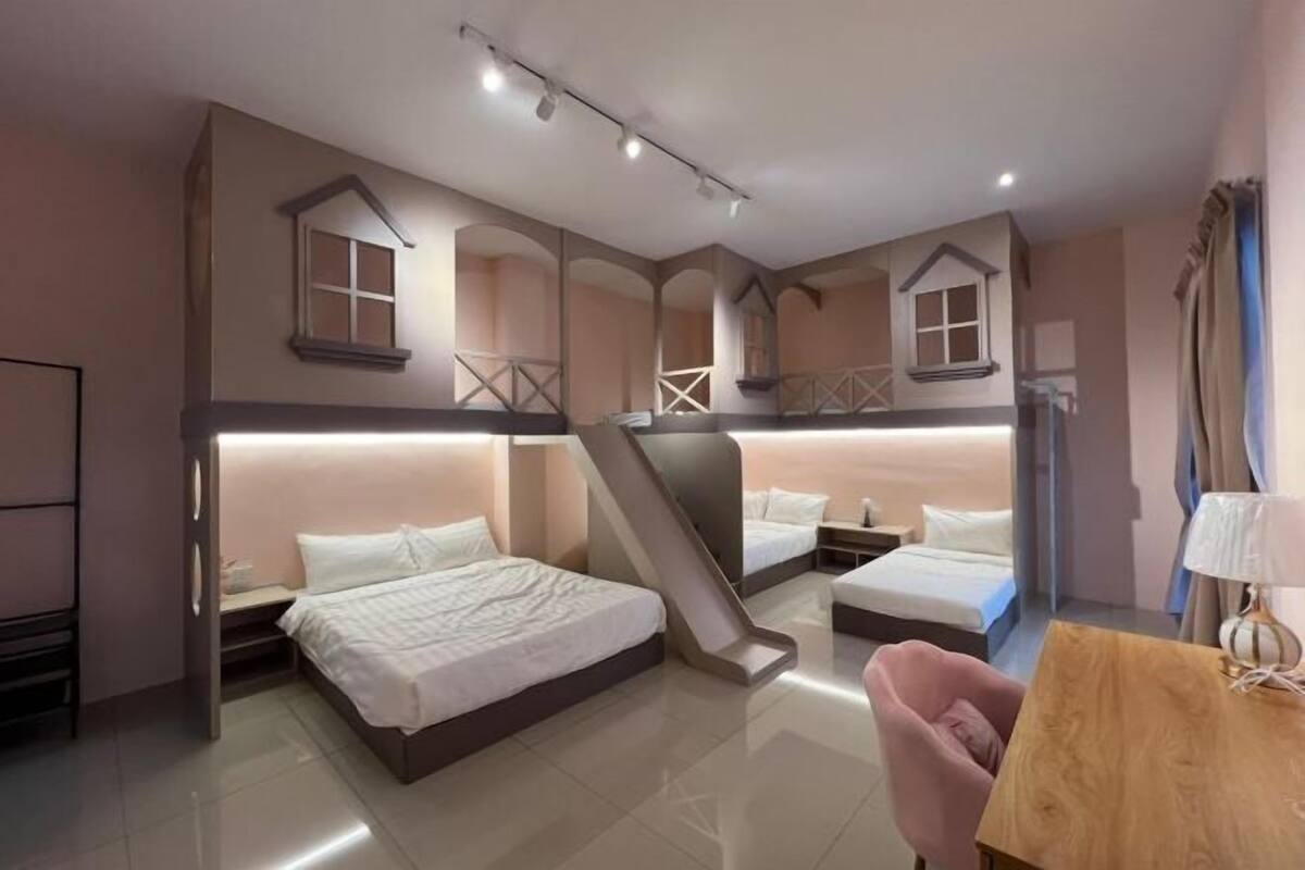 A hotel room with a bunk bed, a desk, a chair, and a staircase.