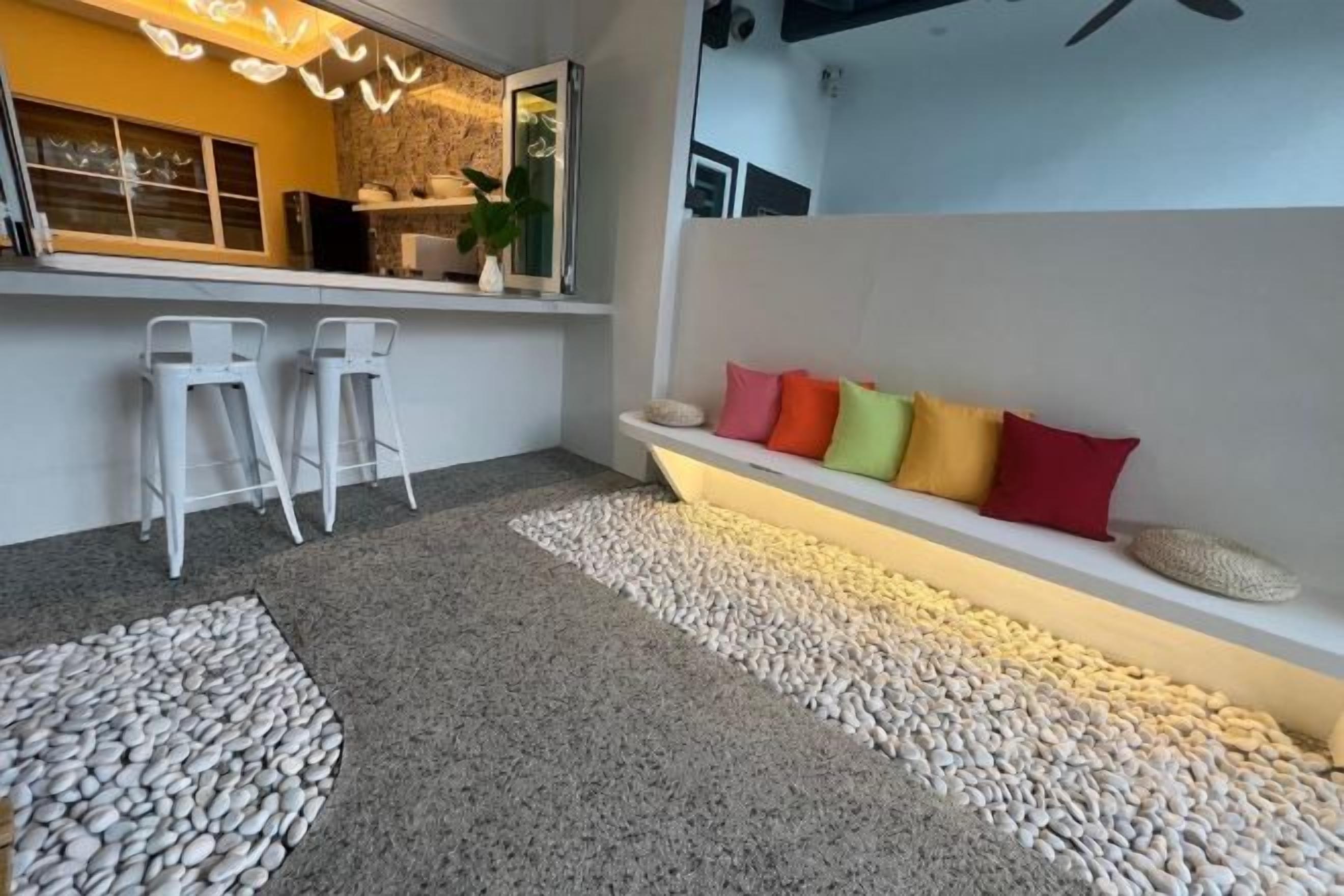 A modern interior with a bar area, seating with colorful cushions, and a pebble-patterned floor.