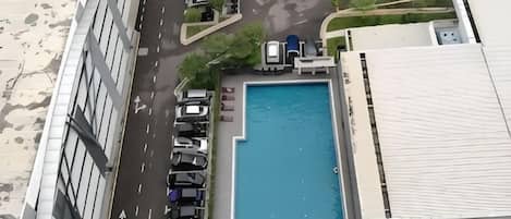 Vue aérienne d’un bâtiment doté d’une piscine, d’un parking et d’une route.
