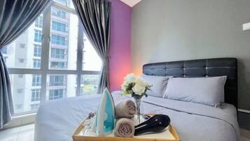 A hotel room with a bed, a tray with an iron, towels, and a vase of flowers.