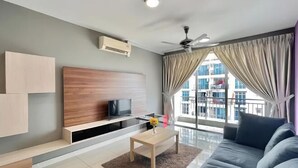 Una sala de estar moderna con un sofá, una mesa de centro, un televisor sobre un mueble de madera y un gran ventanal con cortinas.