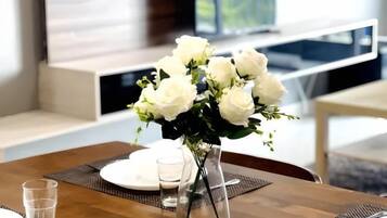 Een eettafel met een vaas witte bloemen, borden en glazen.