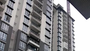 Un edificio residencial alto con varios balcones, una piscina y follaje circundante.