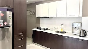 A modern kitchen with dark wood cabinets, a stainless steel refrigerator, a coffee machine, and a sink. - D'Ambience Isotto Suite by Antlerzone (Plentong)