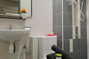 Une salle de bain équipée d’un lavabo, de toilettes, d’une douche et d’un porte-serviettes.