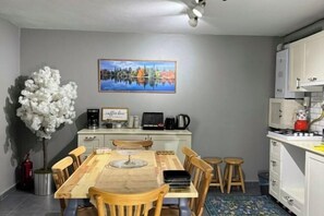 A compact kitchen with a dining area, a coffee machine, and a painting on the wall.