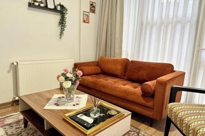 A living room with a brown sofa, a coffee table with a glass top, and a patterned rug.