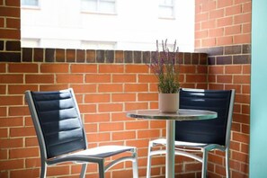 Une petite table avec deux chaises, une plante en pot et un mur de briques.