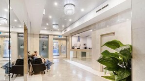 Eine geräumige Lobby mit einer Rezeption, einer Sitzecke und einer großen Pflanze.