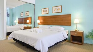 Ein Hotelzimmer mit einem großen Bett, zwei Nachttischen mit Lampen, einem Holzkopfteil und einem großen Spiegel.